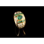 A diamond and emerald ring
Set in gold with carré cut emeralds, one oval cut emerald and 24