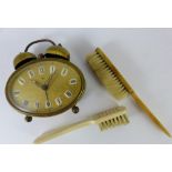 Two antique brushes and an oval brass mechanical alarm clock