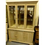 Limed oak glazed wall unit with two glass shelves and lights to top.