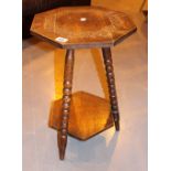 Carved octagonal oak topped table with three bobbin turned legs and under tier