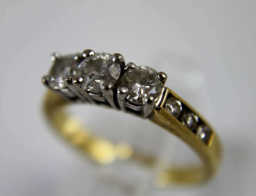 18 ct yellow gold three diamond set ring with diamond set shoulders, size I.