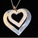 White metal necklace with a white metal pendant in the shape of two hearts