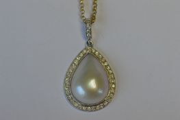 An 18ct white gold teardrop pearl pendant with diamond border and loop top on fine link chain.