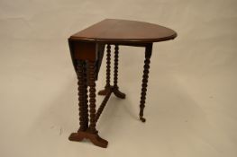 A small circular Sutherland table with turned supports. Est. £50 - £60.