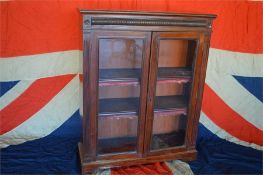 An Edwardian carved bookcase with glazed doors on bracket feet. Est. £200 - £250.