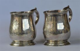 A good rare pair of baluster shaped half pint mugs on tapered pedestal feet and scroll decorated