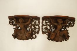A pair of Indian brackets with heavily carved figures. Est. £120 - £140.