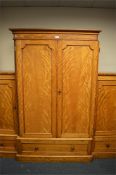 A satin birch triple wardrobe on pedestal base. Est. £250 - £300.