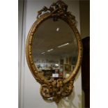 An oval gilt wall mirror moulded with scrolls and candle mount. Est. £20 - £30.