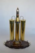 A rare massive dinner gong in the form of three old brass war shells on oak circular pedestal base