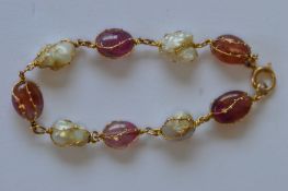 An Antique gold pearl and pink cabochon gem set bracelet. Est. £250 - £300.