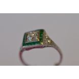 An attractive Art Deco Emerald and Diamond cluster ring with engraved shoulders decorated with