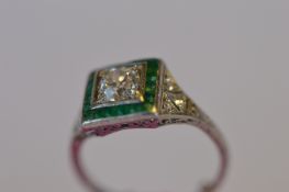 An attractive Art Deco Emerald and Diamond cluster ring with engraved shoulders decorated with