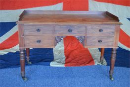 A mahogany five drawer desk  with galleried border and turned legs. Est. £50 - £60.