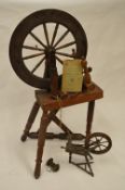 A large spinning wheel together with a similar smaller example. Est. £30 - £40.