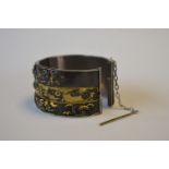 A good quality rare shakudo bangle with three panels heavily decorated with Japanese figures, with