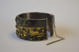 A good quality rare shakudo bangle with three panels heavily decorated with Japanese figures, with