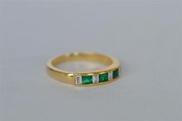 An attractive emerald and diamond baguette cut half eternity ring in 18ct rub-over mount. Est. £