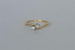 A small diamond two stone crossover ring in 18ct claw mount. Est. £40 - £50.