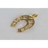 A heavy rose gold pendant in the form of a horseshoe set with nine diamonds with loop top. Approx