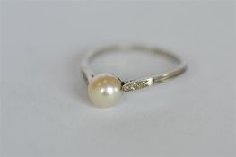 A pearl single stone ring set with diamond shoulders. Est. £220 - £250.