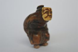 A Japanese miniature ivory and wood netsuke shaped as a bent over figure of a man. Est. £70 - £80.