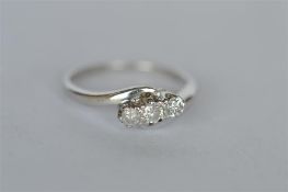 An 18ct white gold diamond three stone crossover ring in claw setting. Est. £120 - £150.