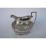 An attractive oval cream jug with embossed decoration on ball feet. Chester 1905. By GN & RH. Approx