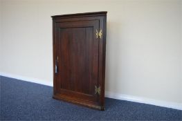 An Antique oak corner cabinet with brass hinges. Est. £40 - £50.