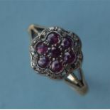 A ruby and diamond daisy shaped cluster ring in 18ct and platinum. Est. £100 - £150.
