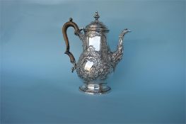 A George IV heavy coffee pot decorated with flowers and scrolls on pedestal base with hinged
