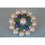 An attractive circular pearl brooch mounted with cabouchon emeralds and sapphires and diamond