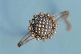 A good quality Victorian 15ct hinged bangle mounted with diamond and pearl bombe centre with
