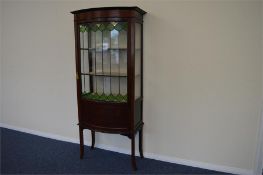 An attractive Art Nouveau glazed bow front display cabinet with lead glazed doors, string inlay