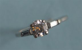A small diamond single stone ring with baguette cut shoulders in platinum mount. Est. £800 - £900.
