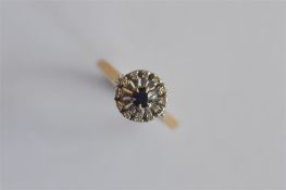 An 18ct circular sapphire and diamond cluster ring in two colour gold. Approx. 5 grams. Est. £
