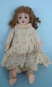 A small French porcelain doll with articulated limbs, wearing lace dress. Marked S F B J 60 Paris to