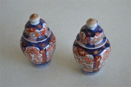 A pair of Imari vases. Approx. 16 cms high. (Damage to lid.) Est. £20 - £30.