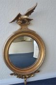 An attractive circular giltwood convex mirror surmounted by a figure of an eagle with outstretched