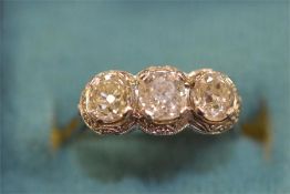 A platinum and diamond three stone ring with engraved setting. Est. £1400 - £1800.