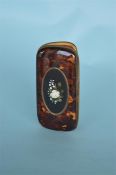 A good quality tortoiseshell pietra dura spectacle case with hinged sides decorated with a flower.