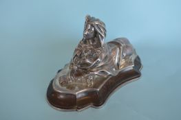 A heavy cast paperweight in the form of a sphinx on wavy base with steel inter liner, presented on