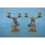 A good pair of cast candleabra in the form of a lady and gent standing beneath a gilt vine holding a