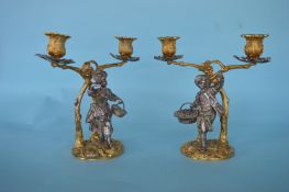 A good pair of cast candleabra in the form of a lady and gent standing beneath a gilt vine holding a