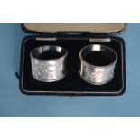 A good quality boxed pair of silver napkin rings with gold floral decoration. Birmingham. 1881. By