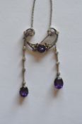 A stylish amethyst and diamond pendant set in gold on fine link chain with two drops mounted with