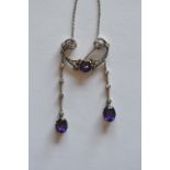 A stylish amethyst and diamond pendant set in gold on fine link chain with two drops mounted with