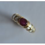 A good quality 18ct oval ruby and emerald cut cluster ring in rub over mount. Approx. 5 grams. The