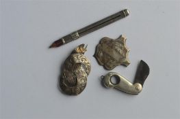 An engraved brooch together with a pencil and ciga