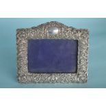 A rectangular silver photo frame with floral and p